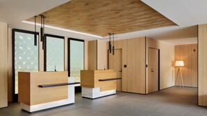 Un espace d’accueil moderne avec des comptoirs de réception en bois, une grande fenêtre et un lampadaire.