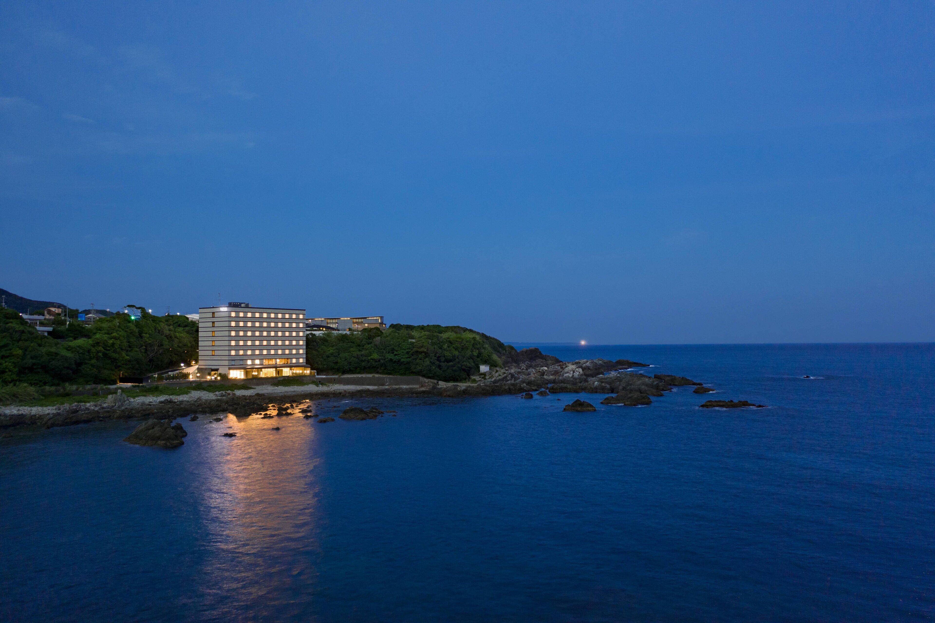 Un hotel costero de diseño moderno, ubicado en una costa rocosa con vista al mar.