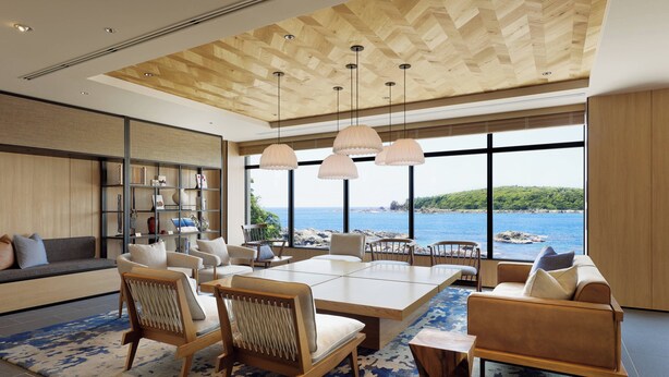Un salon spacieux avec une grande table en bois, des sièges confortables et une vue sur la mer.