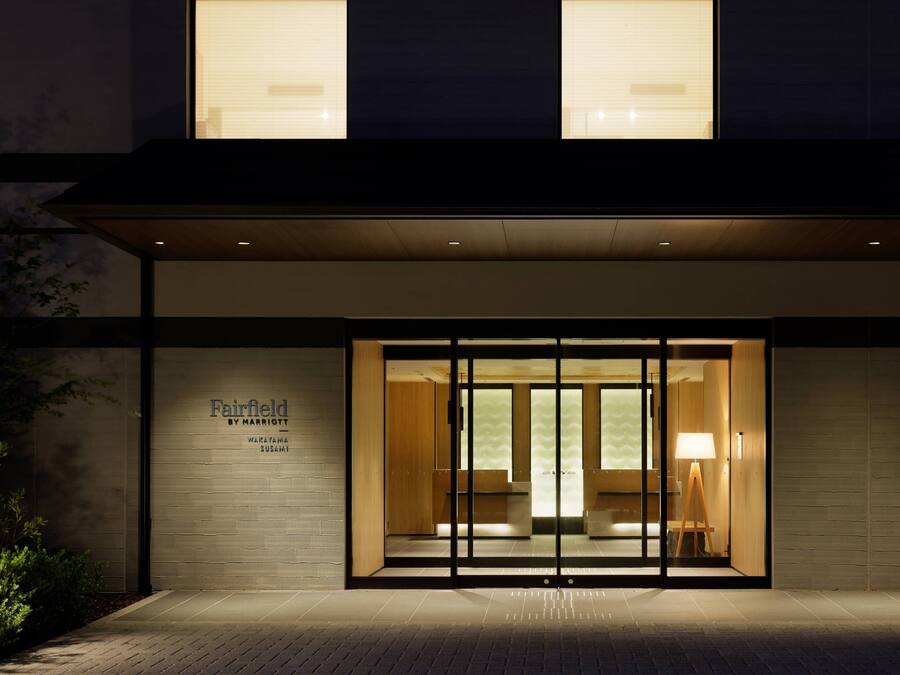 A hotel entrance with a glass door, a sign above the door, and a lamp outside.