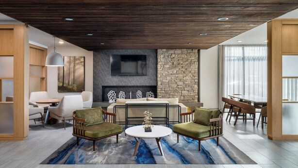 A modern living room with a fireplace, a dining area, and a seating arrangement. - Fairfield Inn & Suites by Marriott Louisville Shepherdsville (Louisville)