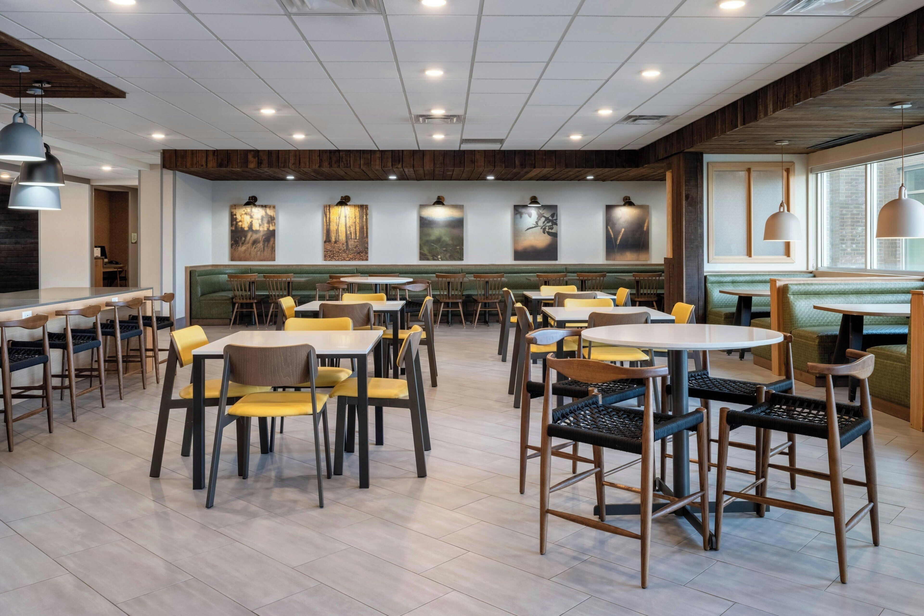 Un comedor amplio con varias mesas y sillas, detalles de madera y obras de arte en las paredes.