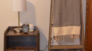 A wooden ladder with a blanket draped over it, a small table with a lamp and an alarm clock, and a carpeted floor. - Quiet Comfort- Adventures Start Here! (Idaho Falls)