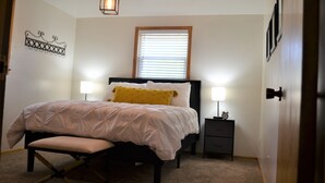 A bedroom with a bed, bedside lamps, a nightstand, and a wall decoration. - Quiet Comfort- Adventures Start Here! (Idaho Falls)