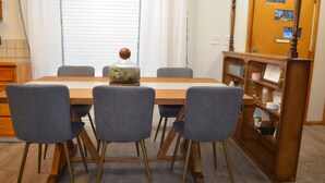 A dining area with a wooden table, four grey chairs, and a decorative glass container on the table. - Quiet Comfort- Adventures Start Here! (Idaho Falls)