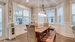 A dining area with a wooden table, wicker chairs, and a hanging light fixture.