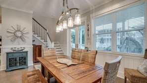 A dining area with a wooden table, wicker chairs, and a chandelier.