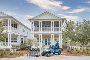A two-story building with a balcony, a golf cart, and bicycles parked in front. - 6 Seater Golf Cart, 5 Bikes! Zero Entry Pool & Beach! - Cool Your Jets at NatureWalk on 30A (Santa Rosa Beach)