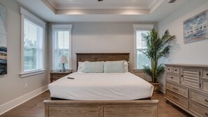 A bedroom with a large bed, wooden headboard, bedside tables, a nightstand, a potted plant, and a dresser. - 6 Seater Golf Cart, 5 Bikes! Zero Entry Pool & Beach! - Cool Your Jets at NatureWalk on 30A (Santa Rosa Beach)