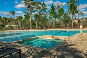 A swimming pool with lounge chairs and a fenced area, surrounded by trees.