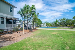 A residential area with a house, a swing set, a basketball court, and a fenced yard.