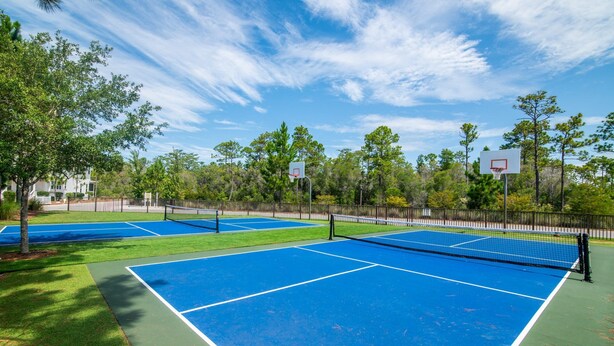 An outdoor tennis court with multiple courts, surrounded by trees and a fence. - 6 Seater Golf Cart, 5 Bikes! Zero Entry Pool & Beach! - Cool Your Jets at NatureWalk on 30A (Santa Rosa Beach)