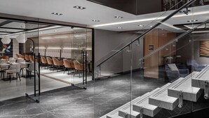 A modern hotel lobby with a glass partition, a staircase, and a seating area with chairs. - Four Points by Sheraton Flushing (Flushing)