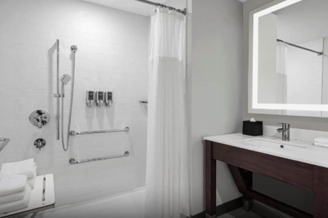 A modern bathroom with a shower, a sink, and a mirror.