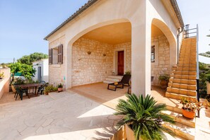 Une maison en pierre dotée d’un patio couvert, d’un espace salon extérieur et d’un escalier.