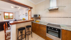 A modern kitchen with a central island, bar stools, a microwave, and an oven.