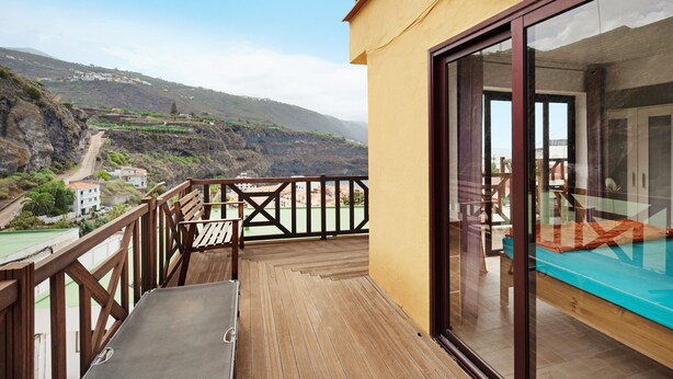 Una terraza de madera con vistas a un valle y edificios lejanos.