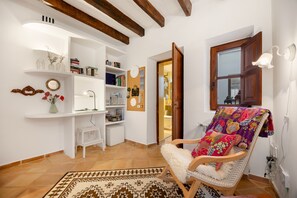 A cozy room with a wooden chair, a white shelf with books, a corkboard with notes, and a patterned rug. - Holiday Home Casa Maria Angela with Sun Terrace, Patio and Wi-Fi (Arta)