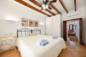 Ein Schlafzimmer mit einem Bett, einem Deckenventilator und einer Tür zu einem anderen Raum.