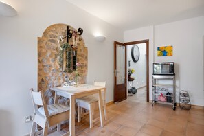 A dining area with a stone wall, a wooden table, and chairs. - Holiday Home Casa Maria Angela with Sun Terrace, Patio and Wi-Fi (Arta)