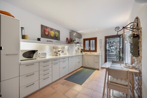 Een moderne keuken met witte kasten, een magnetron en een eethoek met een tafel en stoelen.