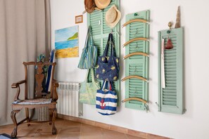A room with a wooden chair, a radiator, and a wall with green shutters and hanging items like hats and bags. - Holiday Home Casa Maria Angela with Sun Terrace, Patio and Wi-Fi (Arta)