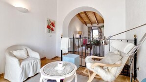 Une pièce chaleureuse avec une chaise blanche, une table ronde et un fauteuil suspendu.