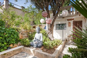 A Buddha statue in a garden with stone walls, potted plants, and hanging lanterns. - Holiday Home Casa Maria Angela with Sun Terrace, Patio and Wi-Fi (Arta)