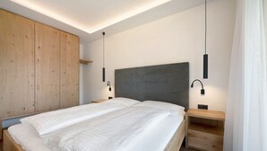Un dormitorio moderno con una cama grande, un armario de madera, mesitas de noche e iluminación colgante.
