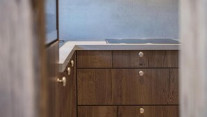 A kitchen with a countertop, wooden cabinets, and a backsplash. - Apartment 'Sommersbergerhof' with Mountain View, Shared Pool and Wi-Fi (Brixen)