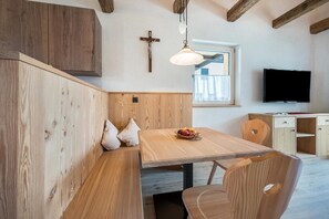 A wooden interior with a bench, table, and a cross on the wall.
