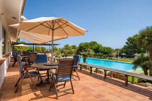 A terrace with outdoor seating, a pool, and a clear view of the surrounding greenery.