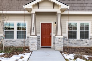 Stylish entrance with a central door, flanked by windows, set amidst a beautifully landscaped area.