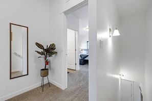 Enter a serene space with a large mirror, a potted plant, and a stylish light fixture.
