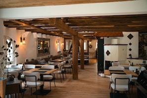 A restaurant with wooden beams, tables, and chairs arranged for dining.