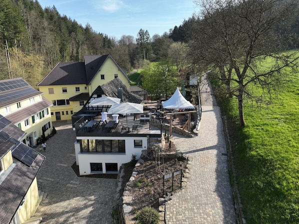 A courtyard with a modern building, traditional houses, and a white tent.