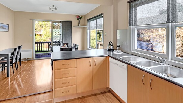 A modern kitchen with wooden cabinets, a black countertop, and a large window.