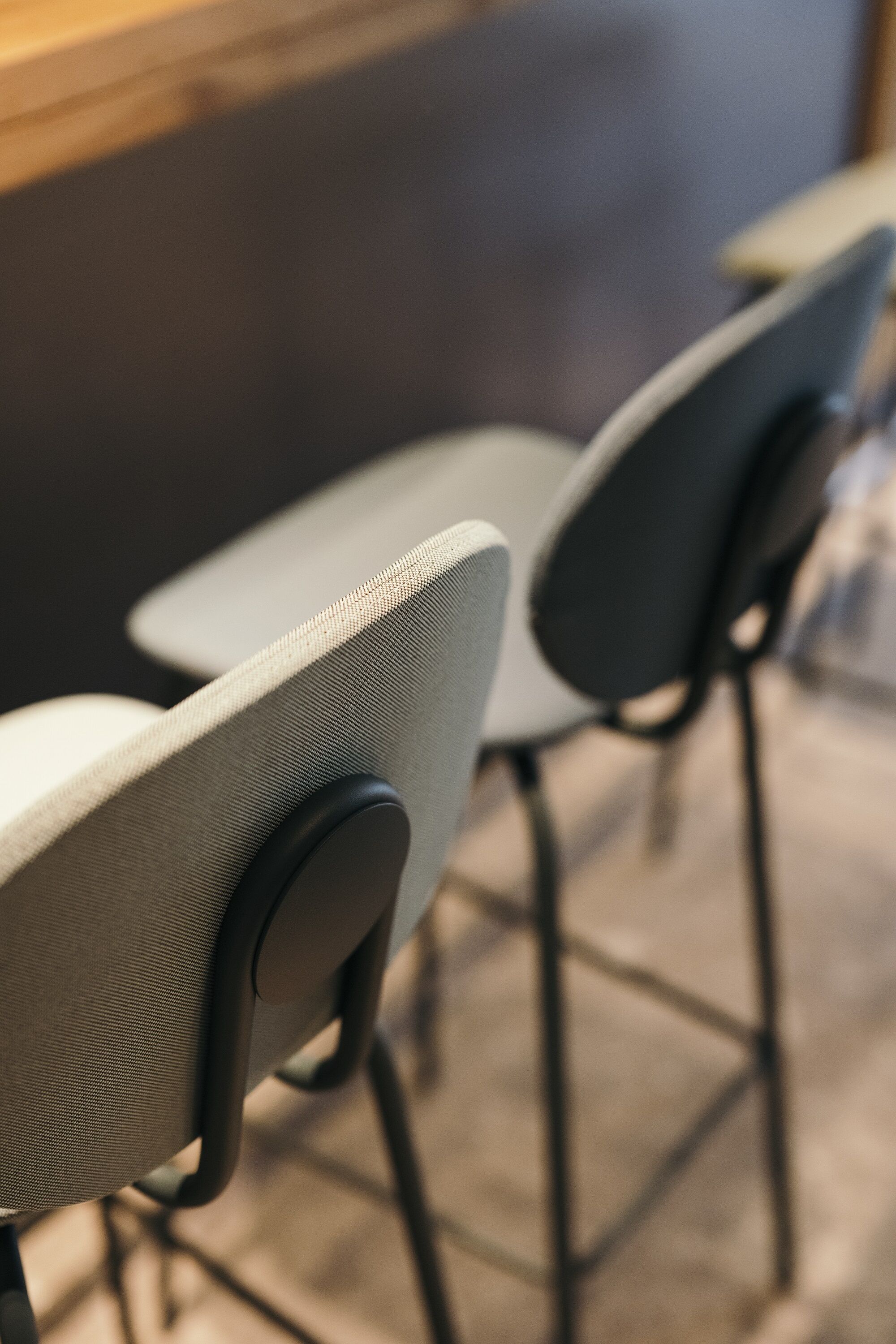 A close-up of a chair with a textured fabric seat and a black armrest.