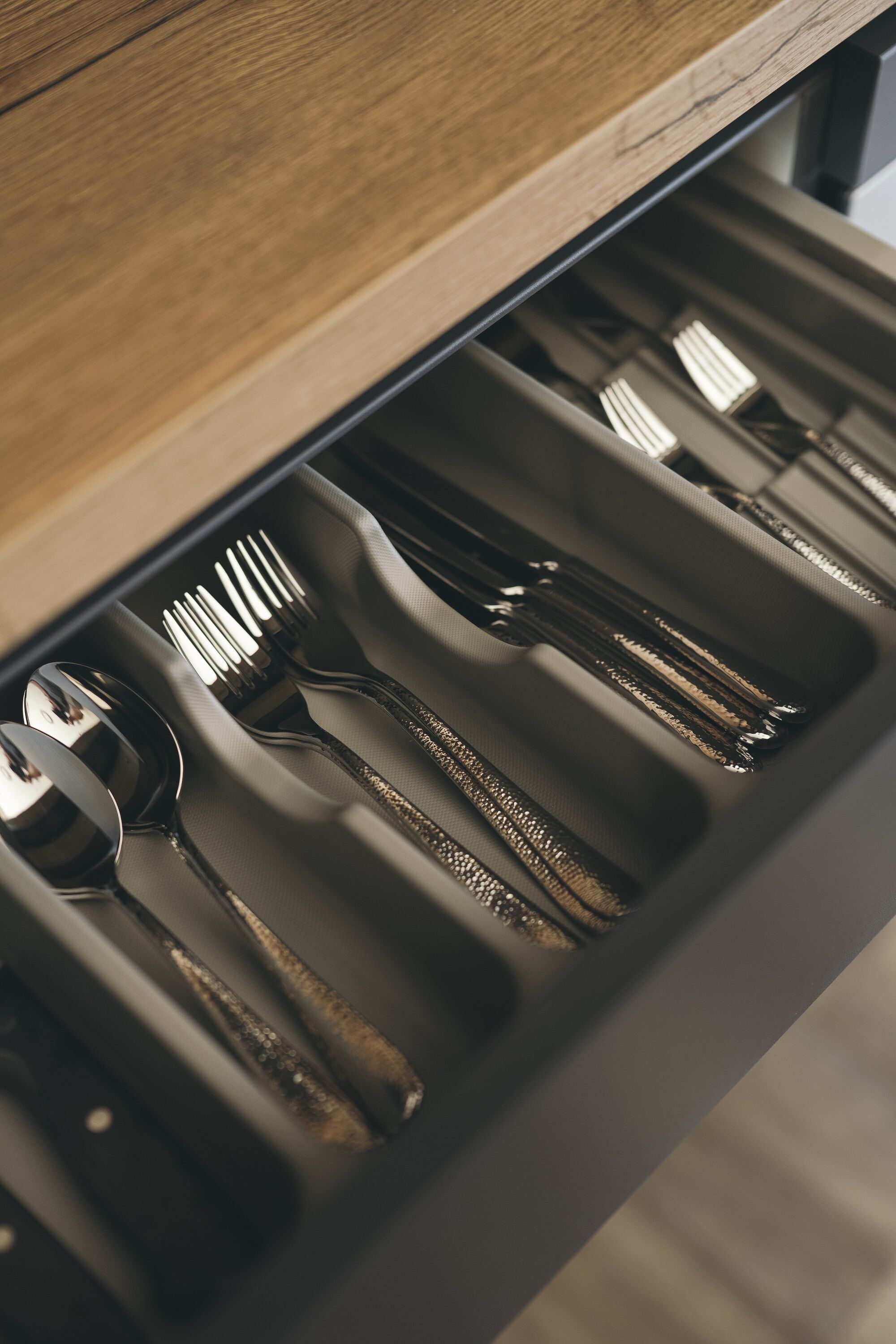 A drawer with utensils including spoons, forks, and knives.