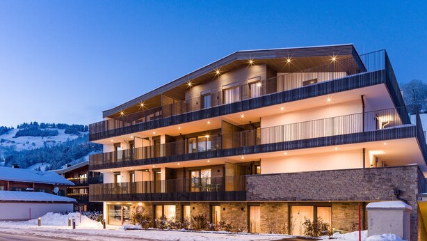 A multi-story hotel with balconies, a stone facade, and a view of a snowy landscape. - REMIND Apartments (Brixen im Thale)
