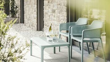 Eine Terrasse im Freien mit Steinmauern, einem Tisch mit Stühlen und einer Weinflasche.
