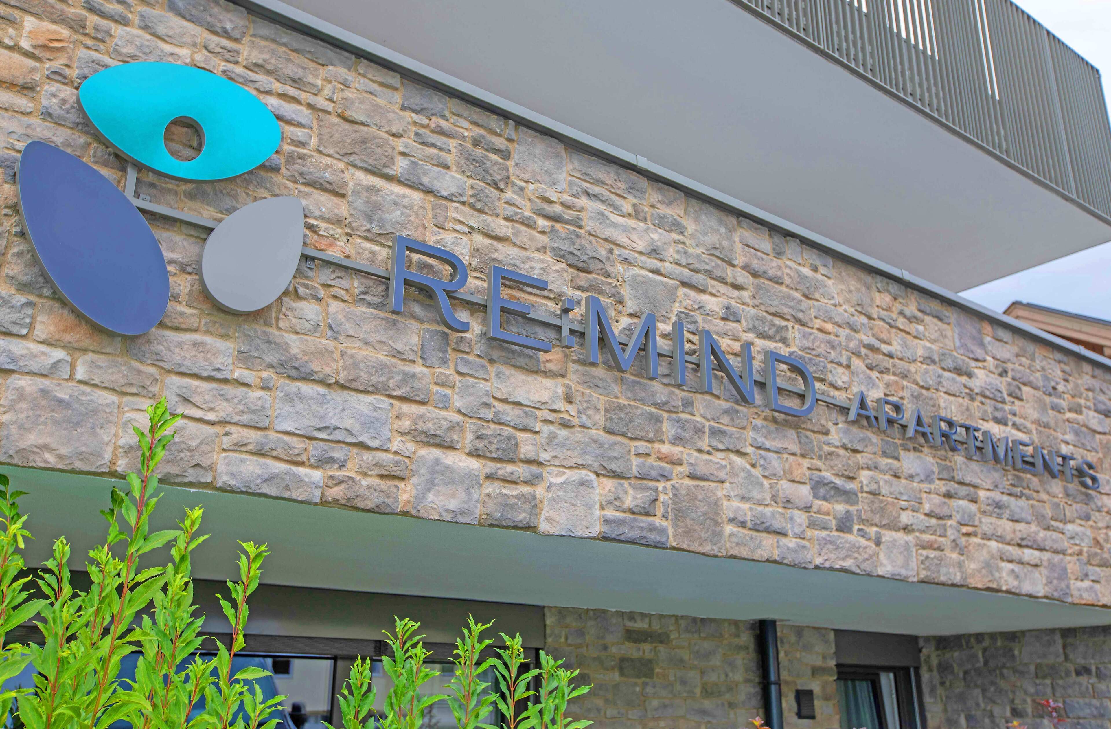 A stone building with the sign "RE-MIND APARTMENTS" and decorative circular elements.