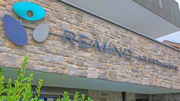 Un bâtiment en pierre avec une enseigne indiquant « RE-MIND APARTMENTS » et des éléments décoratifs de forme circulaire.