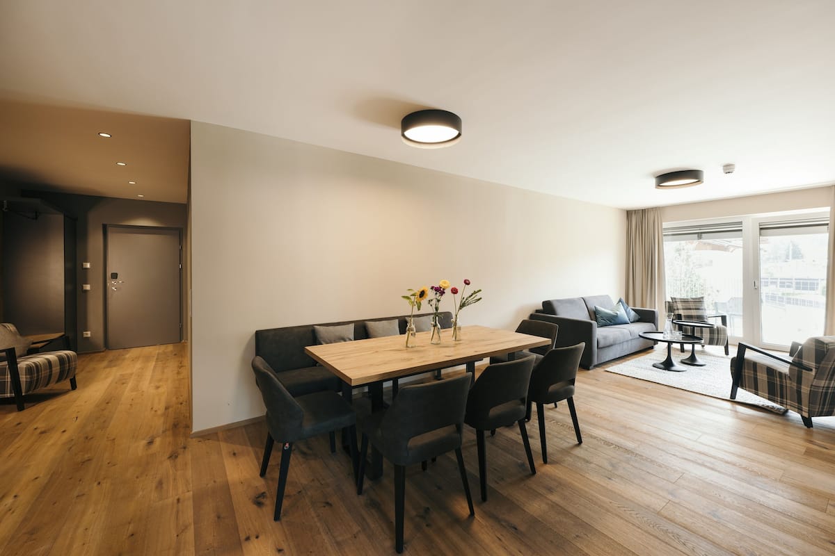 A modern living room with a wooden dining table, black chairs, a sofa, and a coffee table.