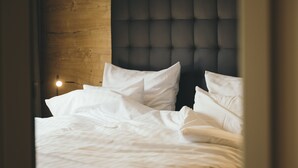 A neatly made bed with white linens and a tufted headboard. - REMIND Apartments (Brixen im Thale)