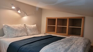 A bedroom with a bed, a wooden cabinet, and a wall-mounted light fixture. - Quiet Lofted Studio at Tomboy Lodge (Telluride)