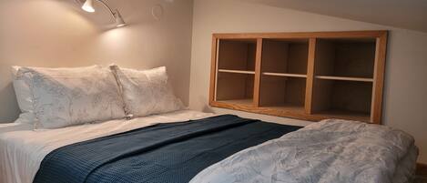 A bedroom with a bed, a wooden cabinet, and a wall-mounted light fixture.