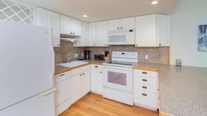 A compact kitchen with white cabinets, a microwave, an oven, and a sink. - Quiet Lofted Studio at Tomboy Lodge (Telluride)