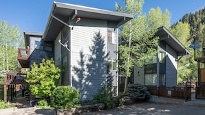 A two-story building with a sloped roof, a deck, and a small garden area. - Quiet Lofted Studio at Tomboy Lodge (Telluride)