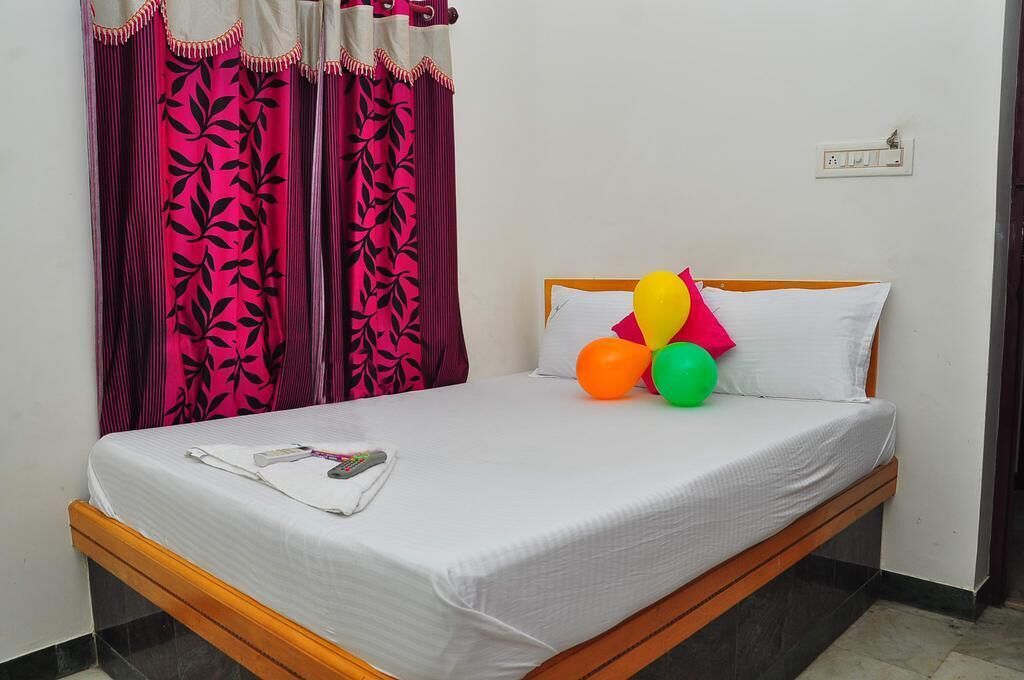A single bed with a white mattress and wooden frame, a white pillow, and a set of colorful balloons on the headboard.